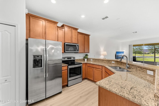 5928 Van Ness Dr, Melbourne, FL 32940 - kitchen featuring appliances with stainless steel finishes, a sink, light stone counters, light wood-style flooring, and brown cabinetry