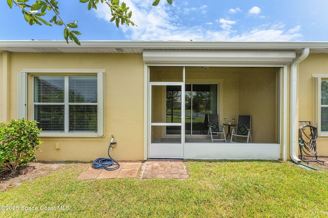 5928 Van Ness Dr, Melbourne, FL 32940 - rear view of property with stucco siding, a sunroom, and a lawn