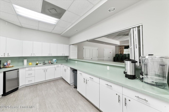 4160 Aberdeen Cir, Rockledge, FL 32955 - kitchen featuring fridge, light countertops, white cabinetry, a paneled ceiling, and light wood-style flooring