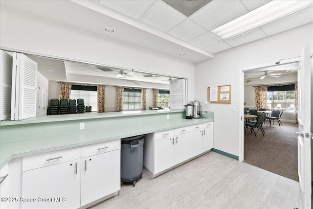 4160 Aberdeen Cir, Rockledge, FL 32955 - kitchen with light countertops, ceiling fan, white cabinets, a drop ceiling, and light wood-style flooring