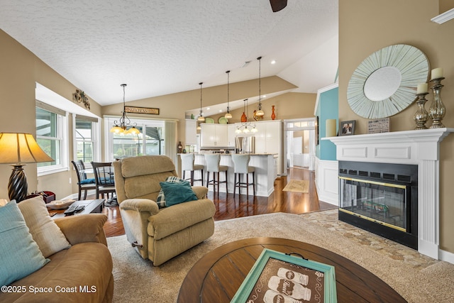 3360 Fort Sumter St, Melbourne, FL 32934 - living area with vaulted ceiling, wood finished floors, a textured ceiling, a chandelier, and a glass covered fireplace