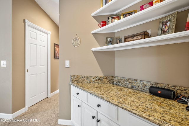 3360 Fort Sumter St, Melbourne, FL 32934 - kitchen featuring open shelves, light colored carpet, white cabinets, baseboards, and light stone countertops