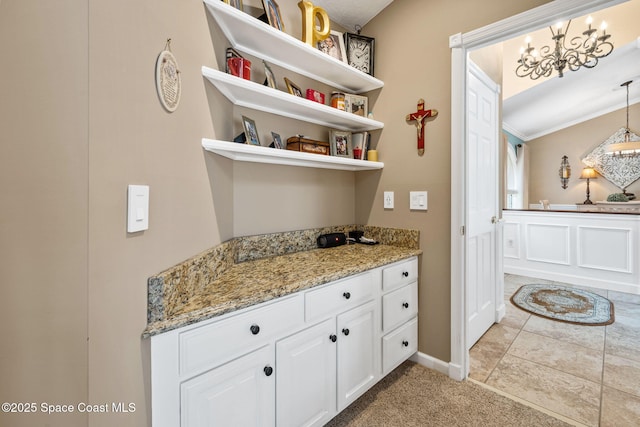 3360 Fort Sumter St, Melbourne, FL 32934 - kitchen with open shelves, white cabinetry, a chandelier, light stone counters, and baseboards