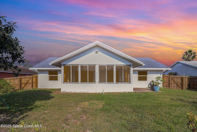 1573 Eagle Ave NW, Palm Bay, FL 32907 - back of house at dusk with a gate, stucco siding, and a sunroom