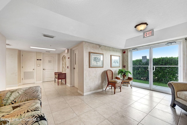 8984 Puerto Del Rio Dr Unit 202, Cape Canaveral, FL 32920 - living area with light tile patterned floors, baseboards, and a textured ceiling