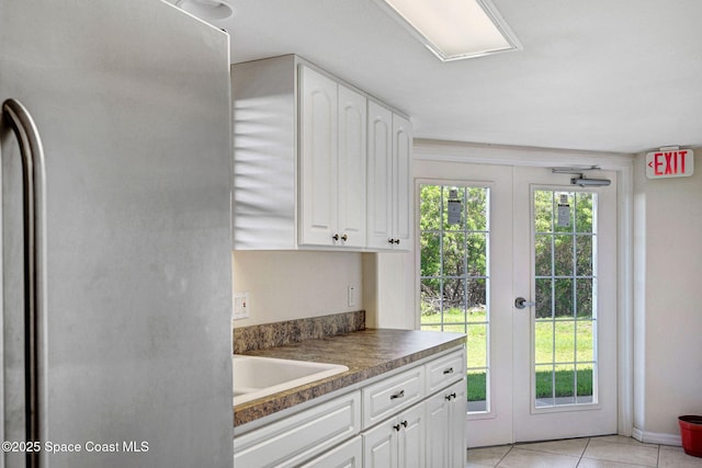 8984 Puerto Del Rio Dr Unit 202, Cape Canaveral, FL 32920 - kitchen featuring freestanding refrigerator, white cabinets, a sink, light tile patterned floors, and french doors
