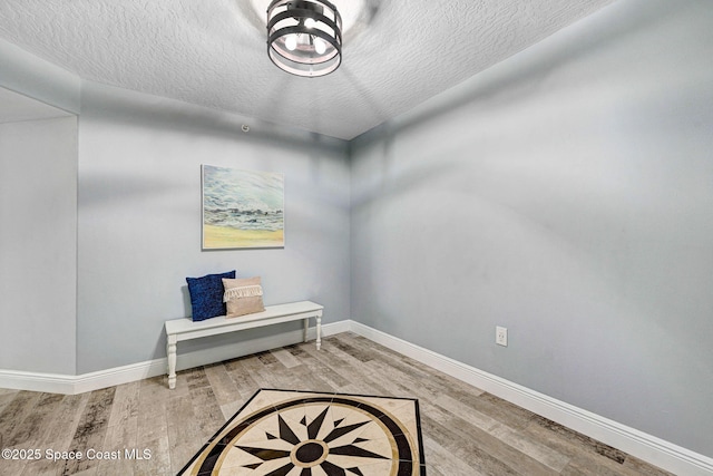 8984 Puerto Del Rio Dr Unit 202, Cape Canaveral, FL 32920 - living area featuring light wood finished floors, a textured ceiling, and baseboards