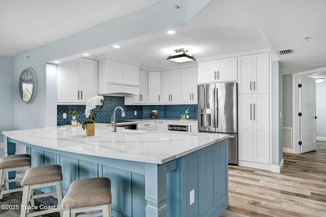 8984 Puerto Del Rio Dr Unit 202, Cape Canaveral, FL 32920 - kitchen with stainless steel fridge, light wood-type flooring, light stone counters, white cabinetry, and recessed lighting