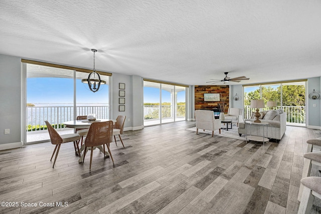 8984 Puerto Del Rio Dr Unit 202, Cape Canaveral, FL 32920 - dining room with wood finished floors, a large fireplace, a textured ceiling, a chandelier, and baseboards