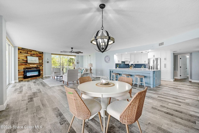 8984 Puerto Del Rio Dr Unit 202, Cape Canaveral, FL 32920 - dining area featuring a chandelier, baseboards, light wood-type flooring, a large fireplace, and a textured ceiling