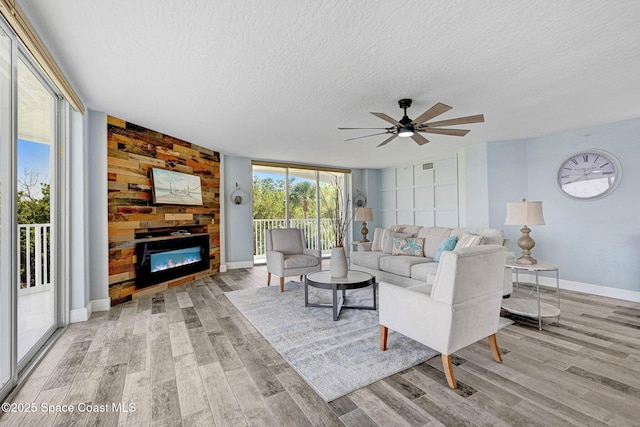 8984 Puerto Del Rio Dr Unit 202, Cape Canaveral, FL 32920 - living area featuring a textured ceiling, wood finished floors, a fireplace, a ceiling fan, and baseboards