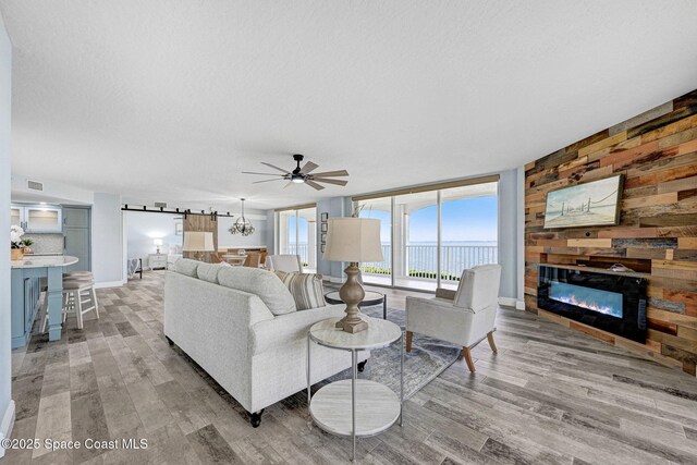 8984 Puerto Del Rio Dr Unit 202, Cape Canaveral, FL 32920 - living room featuring a ceiling fan, wood finished floors, a glass covered fireplace, wood walls, and baseboards