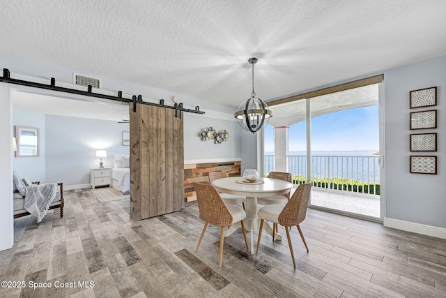 8984 Puerto Del Rio Dr Unit 202, Cape Canaveral, FL 32920 - dining space featuring a barn door, wood finished floors, a water view, a chandelier, and baseboards