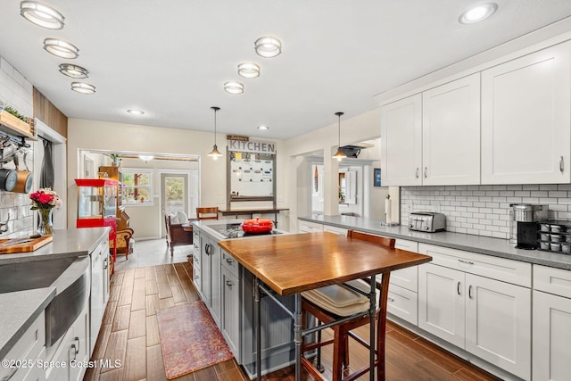420 Tortoise View Cir, Satellite Beach, FL 32937 - kitchen featuring black electric stovetop, backsplash, white cabinets, dark wood-style floors, and hanging light fixtures