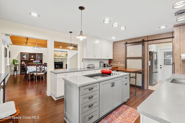 420 Tortoise View Cir, Satellite Beach, FL 32937 - kitchen featuring black electric stovetop, freestanding refrigerator, a fireplace, a barn door, and dark wood finished floors