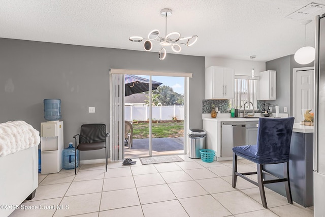 1889 Nanton St NW, Palm Bay, FL 32907 - kitchen with stainless steel dishwasher, a textured ceiling, white cabinets, hanging light fixtures, and a chandelier