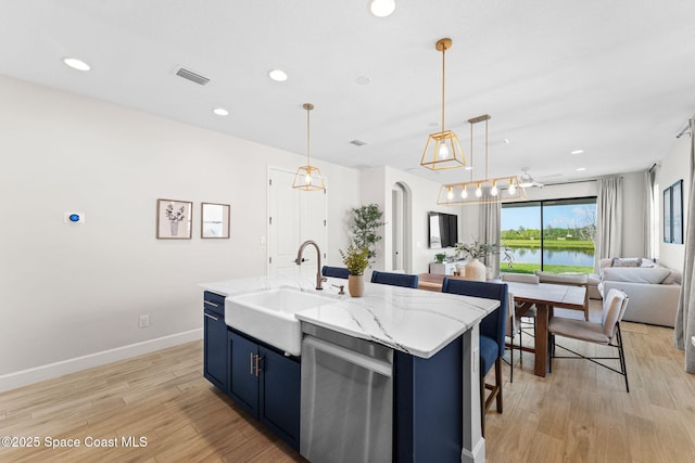 3015 Blazing Star Dr, Melbourne, FL 32940 - kitchen with stainless steel dishwasher, blue cabinetry, a sink, open floor plan, and light wood-style flooring