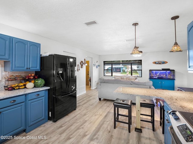 1475 Mars St, Merritt Island, FL 32953 - kitchen featuring black fridge, blue cabinetry, backsplash, light wood-style flooring, and decorative light fixtures