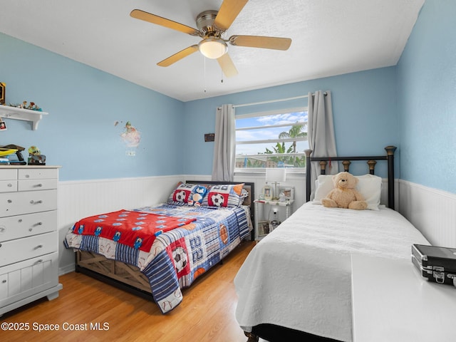 1475 Mars St, Merritt Island, FL 32953 - bedroom with wood finished floors, wainscoting, and ceiling fan