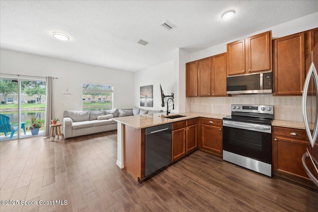 2500 Revolution St Unit 103, Melbourne, FL 32935 - kitchen with stainless steel appliances, a sink, brown cabinets, and a peninsula