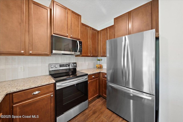 2500 Revolution St Unit 103, Melbourne, FL 32935 - kitchen featuring stainless steel appliances, dark wood finished floors, backsplash, and brown cabinets