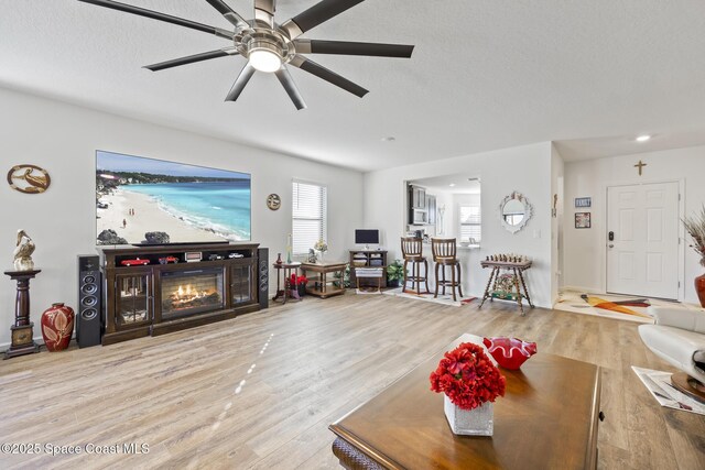 4554 Magenta Isles Dr, Melbourne, FL 32904 - living area with ceiling fan, wood finished floors, a glass covered fireplace, and a textured ceiling