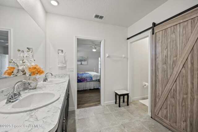 4554 Magenta Isles Dr, Melbourne, FL 32904 - ensuite bathroom featuring double vanity, a textured ceiling, ceiling fan, baseboards, and tile patterned floors