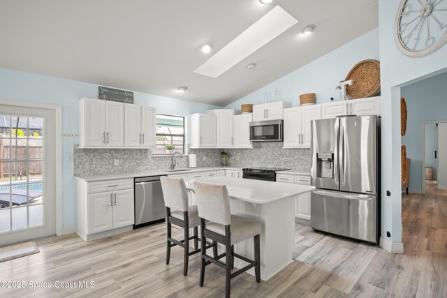 149 Kyle Ct NE, Palm Bay, FL 32907 - kitchen with stainless steel appliances, light countertops, a skylight, tasteful backsplash, and white cabinets