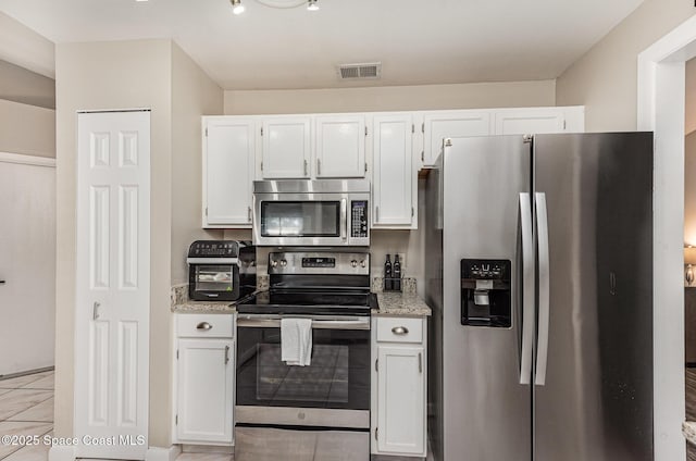 5145 Fay Blvd, Cocoa, FL 32927 - kitchen with appliances with stainless steel finishes, white cabinetry, light tile patterned flooring, and light stone countertops