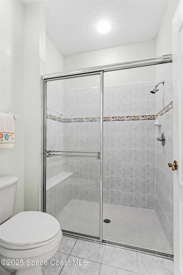 4341 Aberdeen Cir, Rockledge, FL 32955 - full bath featuring toilet, a textured ceiling, a shower stall, and tile patterned floors