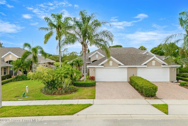 4341 Aberdeen Cir, Rockledge, FL 32955 - view of front of house with stucco siding, a front yard, decorative driveway, and an attached garage
