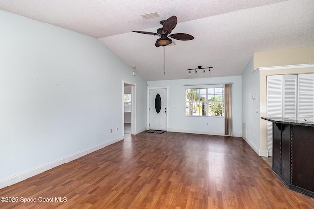 409 Americana Blvd NE, Palm Bay, FL 32907 - unfurnished living room with ceiling fan, wood finished floors, vaulted ceiling, baseboards, and a textured ceiling