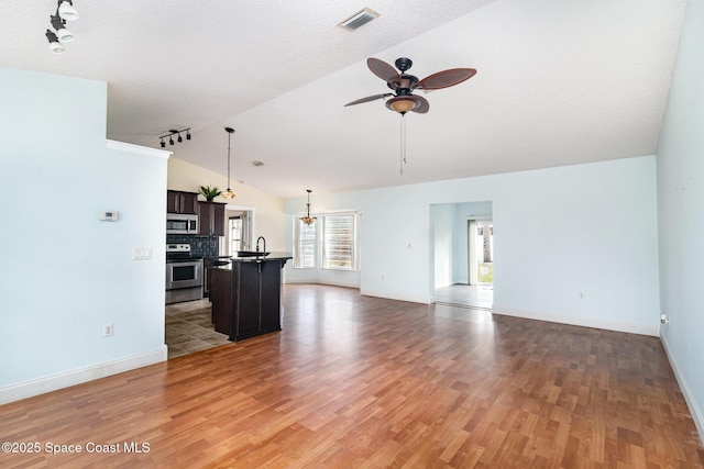 409 Americana Blvd NE, Palm Bay, FL 32907 - unfurnished living room featuring lofted ceiling, track lighting, a ceiling fan, light wood finished floors, and baseboards
