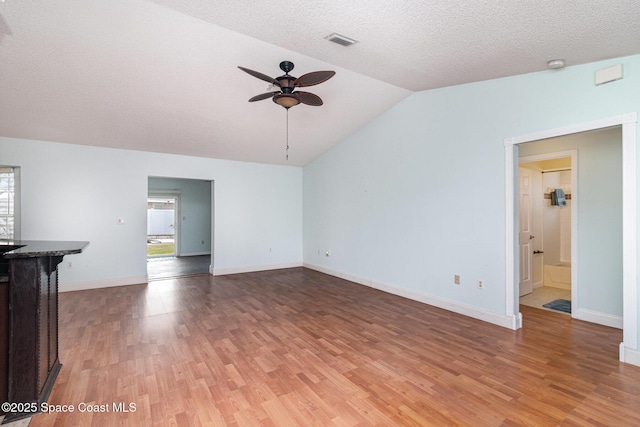 409 Americana Blvd NE, Palm Bay, FL 32907 - unfurnished living room with ceiling fan, lofted ceiling, light wood-style floors, baseboards, and a textured ceiling