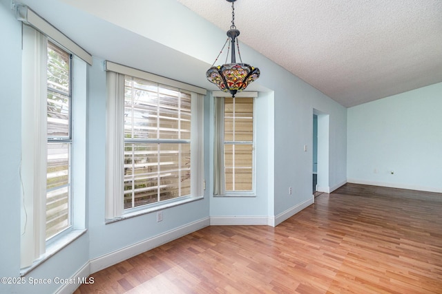 409 Americana Blvd NE, Palm Bay, FL 32907 - unfurnished dining area with wood finished floors, a textured ceiling, baseboards, and vaulted ceiling