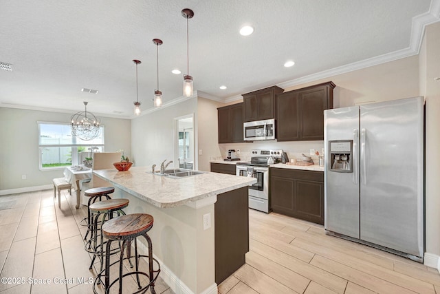 910 Swiss Pointe Ln, Rockledge, FL 32955 - kitchen with appliances with stainless steel finishes, ornamental molding, dark brown cabinetry, a breakfast bar area, and light countertops