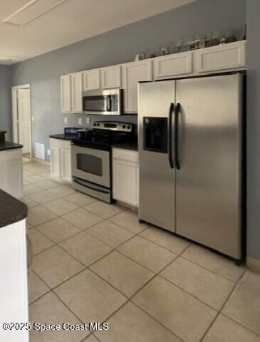 982 Colonial Ave SE, Palm Bay, FL 32909 - kitchen with appliances with stainless steel finishes, dark countertops, white cabinets, and light tile patterned flooring