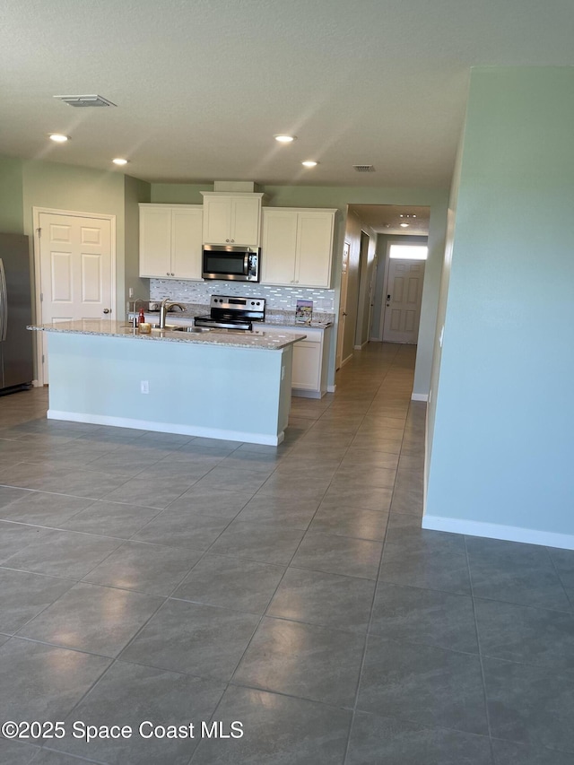 7055 Topaz Dr, Grant-Valkaria, FL 32949 - kitchen featuring appliances with stainless steel finishes, decorative backsplash, white cabinetry, light stone counters, and recessed lighting