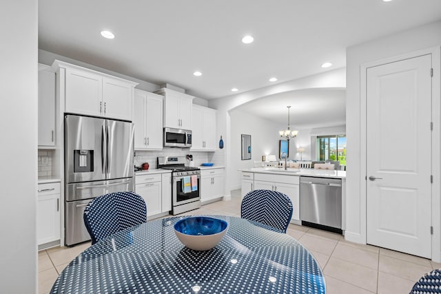2611 Ballydoyle Ln, Melbourne, FL 32940 - kitchen featuring appliances with stainless steel finishes, a chandelier, decorative backsplash, light tile patterned floors, and white cabinetry