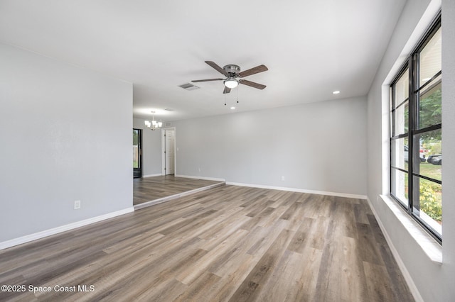 1521 Baker St NE, Palm Bay, FL 32907 - spare room featuring a chandelier, ceiling fan, baseboards, wood finished floors, and recessed lighting