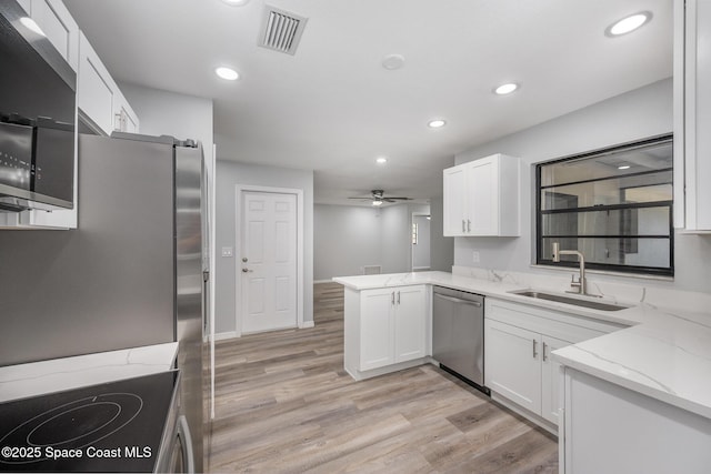 1521 Baker St NE, Palm Bay, FL 32907 - kitchen featuring appliances with stainless steel finishes, a sink, white cabinets, recessed lighting, and light wood finished floors