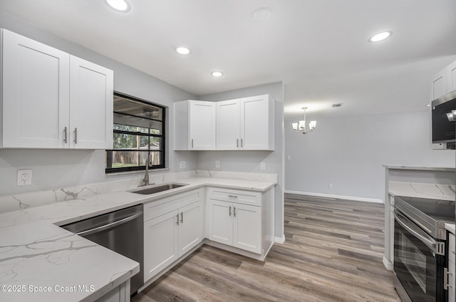 1521 Baker St NE, Palm Bay, FL 32907 - kitchen featuring appliances with stainless steel finishes, a sink, white cabinets, light stone counters, and recessed lighting