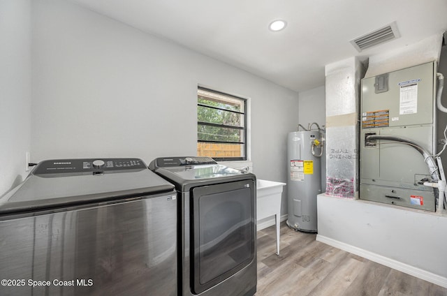 1521 Baker St NE, Palm Bay, FL 32907 - laundry room with electric water heater, washing machine and clothes dryer, light wood-type flooring, baseboards, and heating unit