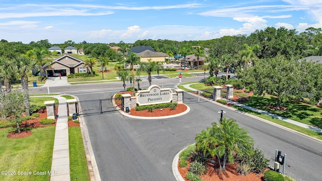 422 Moray Dr SW, Palm Bay, FL 32908 - view of asphalt street with a gate, sidewalks, and curbs