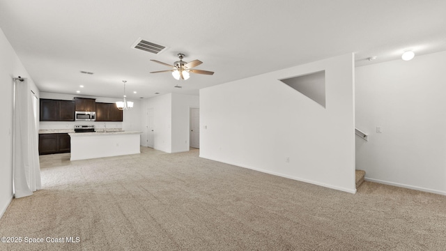 422 Moray Dr SW, Palm Bay, FL 32908 - unfurnished living room featuring light colored carpet, ceiling fan, stairs, baseboards, and a chandelier