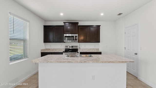 422 Moray Dr SW, Palm Bay, FL 32908 - kitchen with stainless steel appliances, light tile patterned floors, light countertops, dark brown cabinetry, and a center island with sink