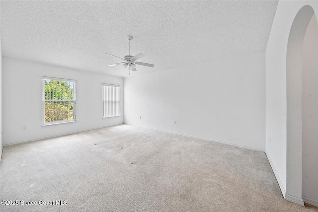 3380 Toledo Ave, Palm Bay, FL 32908 - spare room featuring arched walkways, a ceiling fan, a textured ceiling, carpet flooring, and baseboards