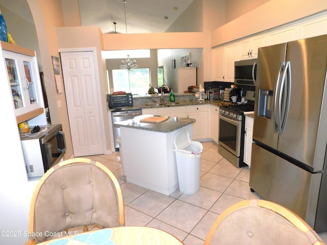 1076 Pine Creek Cir NE, Palm Bay, FL 32905 - kitchen featuring stainless steel appliances, a chandelier, white cabinets, light tile patterned floors, and high vaulted ceiling
