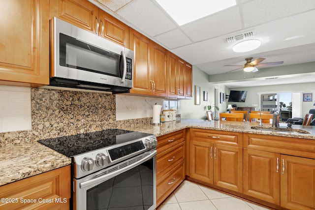 1700 N Atlantic Ave Unit 133, Cocoa Beach, FL 32931 - kitchen featuring stainless steel appliances, light stone countertops, ceiling fan, and brown cabinets