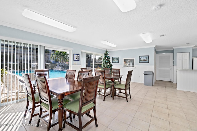 1700 N Atlantic Ave Unit 133, Cocoa Beach, FL 32931 - dining room featuring ornamental molding, a textured ceiling, a wainscoted wall, and light tile patterned floors